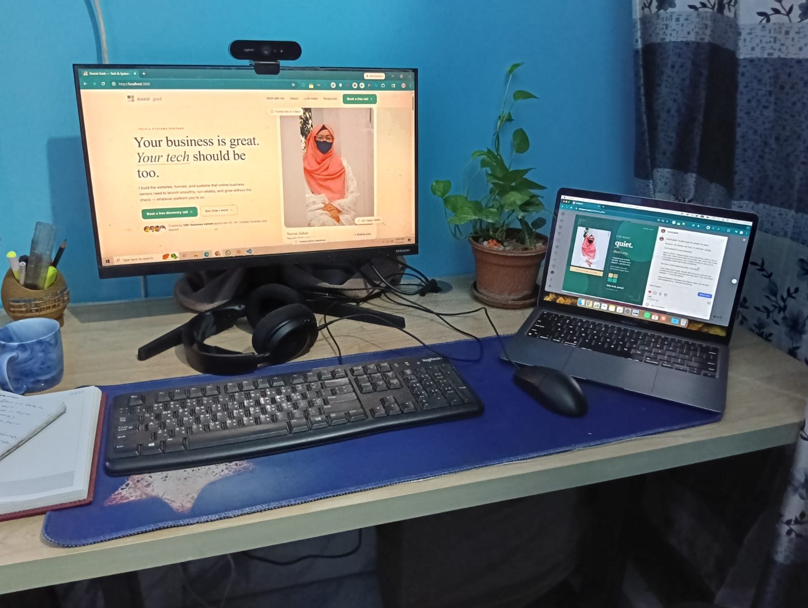 Nusrat's workspace: monitor, laptop, plant, blue mug, notebook