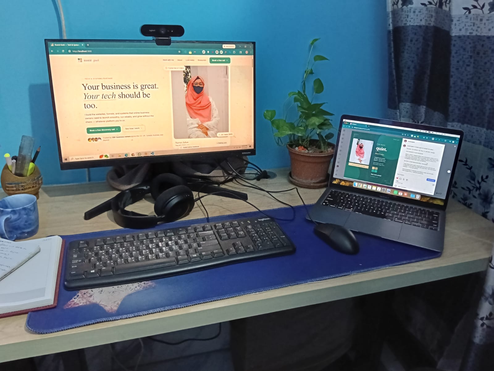 Nusrat's workspace: monitor, laptop, plant, blue mug, notebook